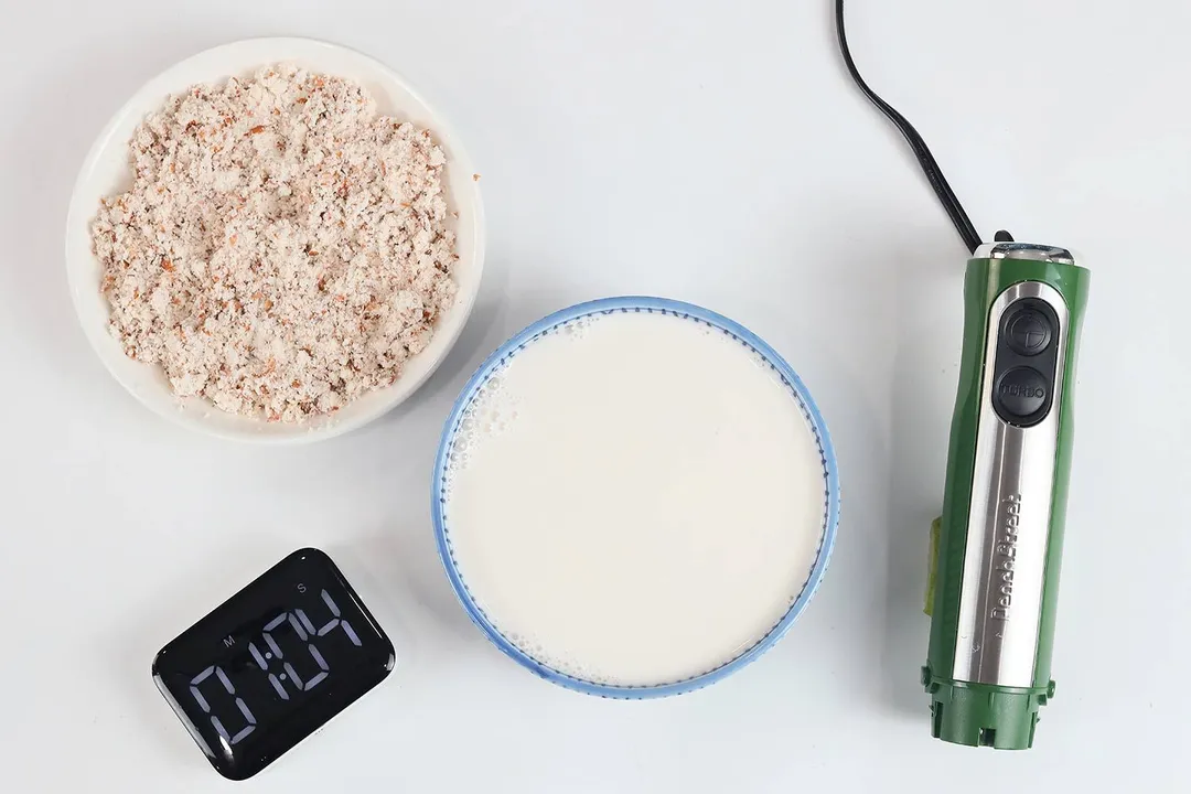 A white plate of almond pulp and a bowl of milk produced by the Peach Street stick blender within 1 minute and 04 seconds.