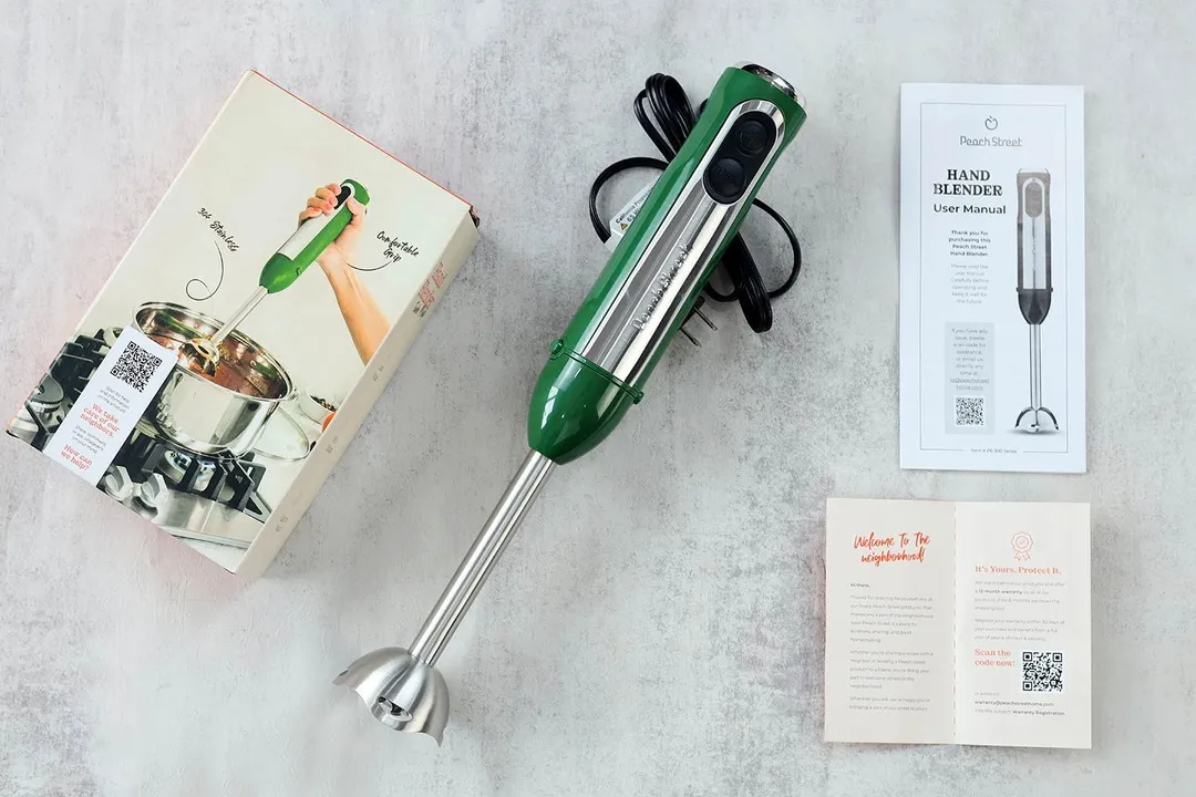 The Peach Street immersion blender lying on a table with its paper carton box and a user’s manual.