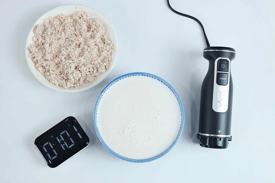 The Ninja CI101 Foodi immersion blender beside its bowl of almond milk and the corresponding almond pulp produced in 1 minute 01 second. 