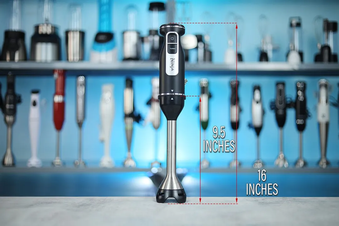 The Ninja Foodi Power Mixer System standing on a table, with the length of its blending shaft being noted to the side as 9.5 inches, and the total length of the unit as 16 inches.  