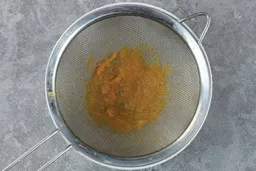A batch of soup pureéd by the  Braun MQ7035X immersion blender is checked for smoothness by being drained through a stainless steel mesh strainer. 