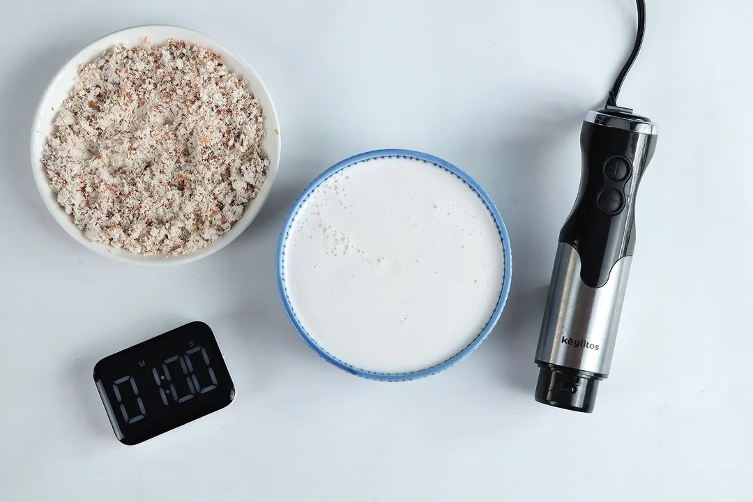The Keylitos 5-in-1 immersion blender beside its bowl of almond milk and the corresponding almond pulp produced in 1 minute.