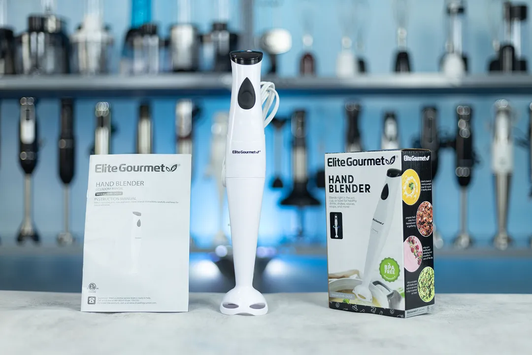 Elite Gourmet Immersion Blender EHB-2425X is standing on a table with its user manual and packaging box