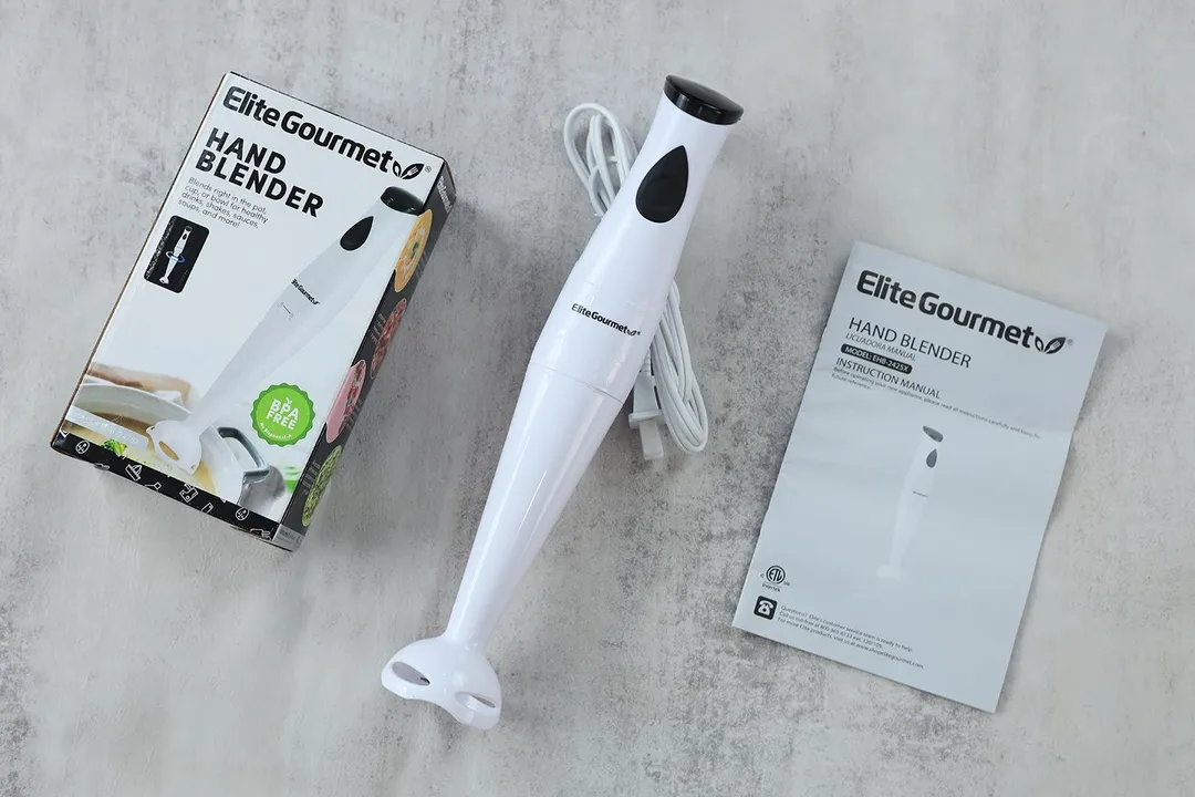 The Elite Gourmet EHB-2425X immersion blender lying on a table with its paper carton box and a user’s manual.