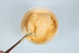 Scooping a spoon of mayonnaise made by the Cuisinart EvolutionX RHB-100TG immersion blender.