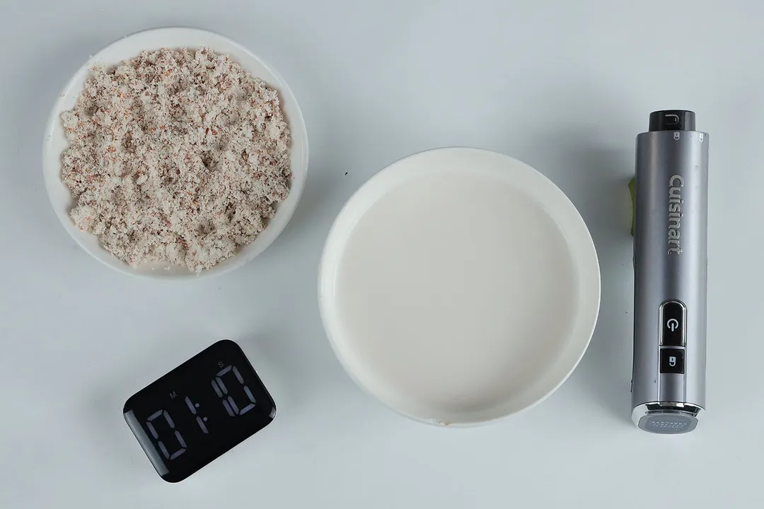 A white plate of almond pulp and a bowl of milk produced by the Cuisinart EvolutionX RHB-100TG stick blender within 1 minute and 10 seconds.