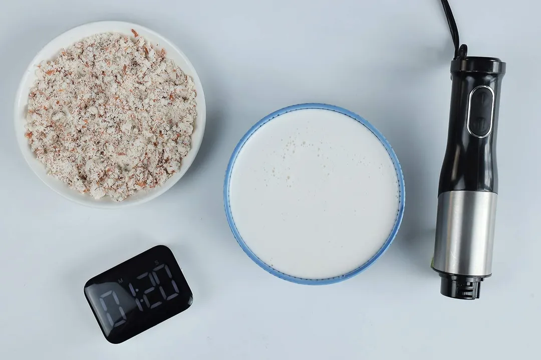A white plate of almond pulp and a bowl of milk produced by theLINKchef stick blender within 1 minute and 20 seconds.