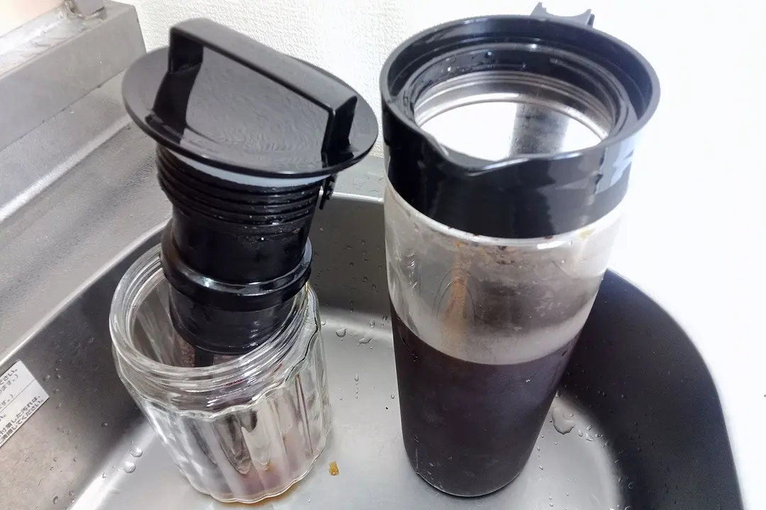 A cold brew coffee maker with the filter just removed after 18 hours of brewing and resting in a glass jar to the right.