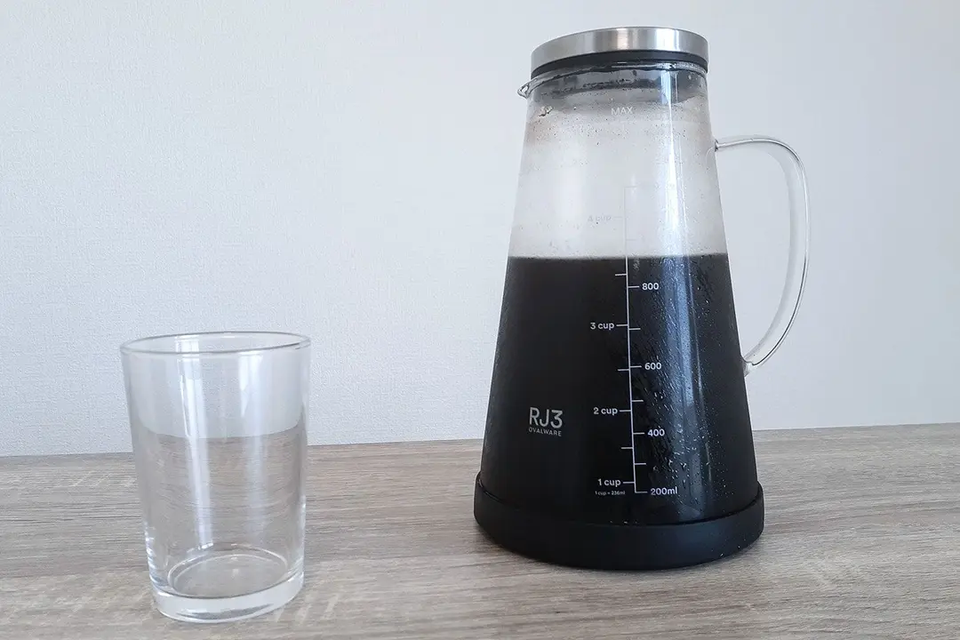 The Ovalware cold brew coffee maker with a freshly produced cold brew and an empty glass to the left.