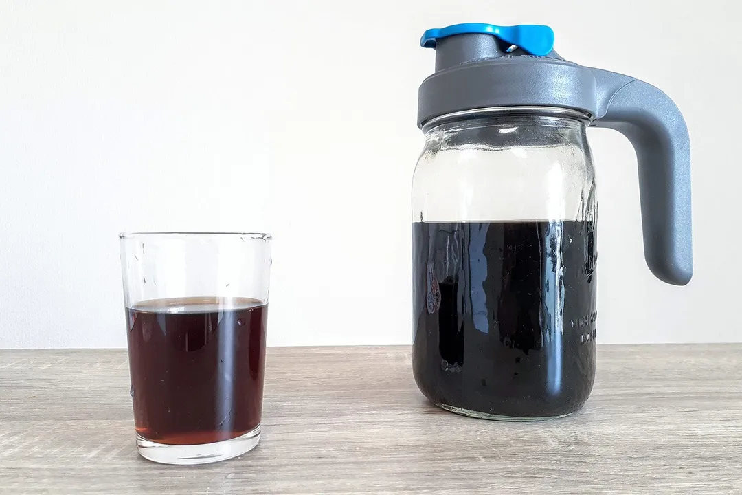 A batch of freshly brewed coffee in the County Line cold brew coffee maker and a glass of coffee to the right.