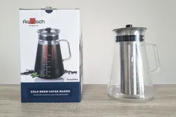 The Aquach cold brew coffee maker glass brew carafe resting to the right of its box.