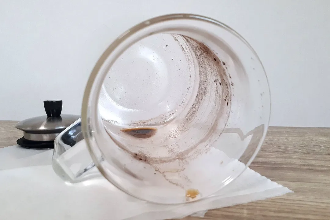 A view inside a cold brew coffee maker glass carafe showing sediment after the brew has been decanted.