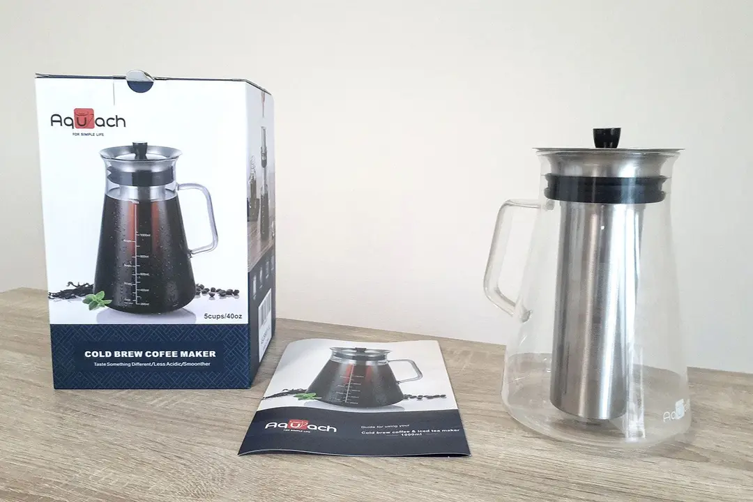 The unboxed Aquuach cold brew coffee maker. On the far left is the box, the user manual, and then the assembled brewer.
