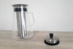 The Aquach cold brew coffee maker glass carafe with the stopper lid resting besides it.