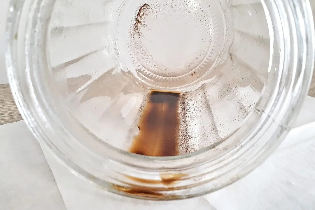 The inside of a glass jar showing sediment left behind after a typical cold brew coffee maker brew.