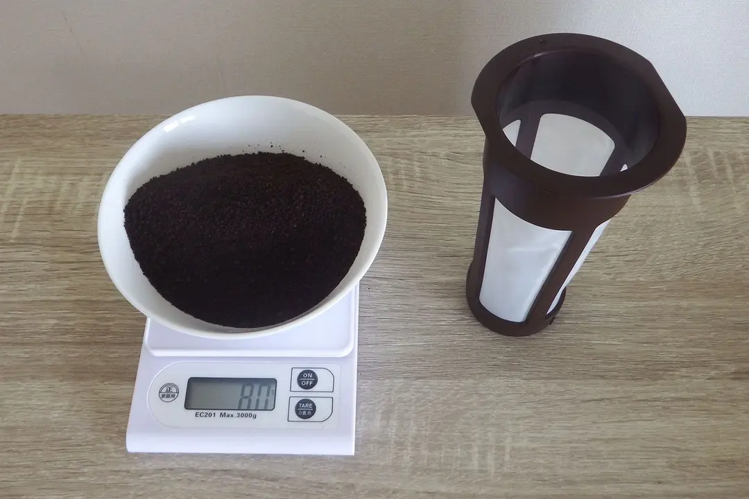 A cold brew coffee immersion filter next to a kitchen scale with a bowl of 80g of coffee grounds measured.