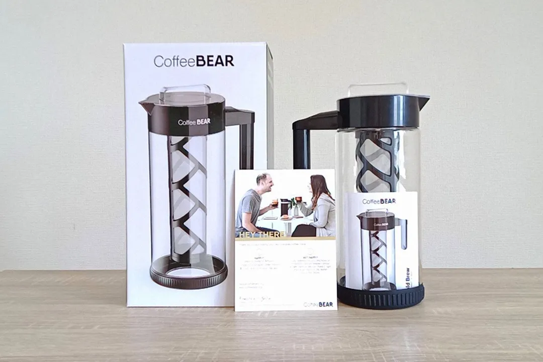 The unboxed Coffee Bear cold brew coffee maker. The box is to the left, the brewer to the right, and the user-guide in front.