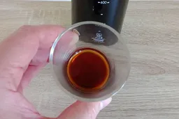 A visual sample of some cold brewed coffee in a glass cup with the penetrating light indicating the brew strength.