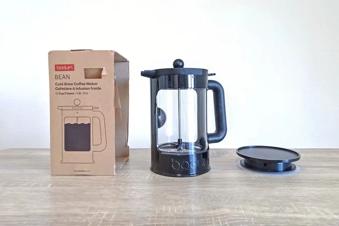 The unboxed Bodum cold brew coffee maker standing between its box and an additional brewing lid.