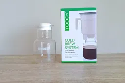 The glass carafe of the Toddy cold brew system standing on a counter next to its box.