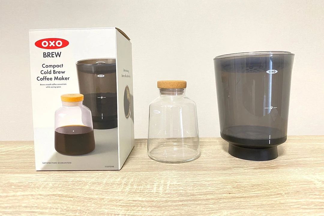The Oxo Compact cold brew coffee maker unboxed with the box to the left, the carafe in the center, and the brew vessel to the right.