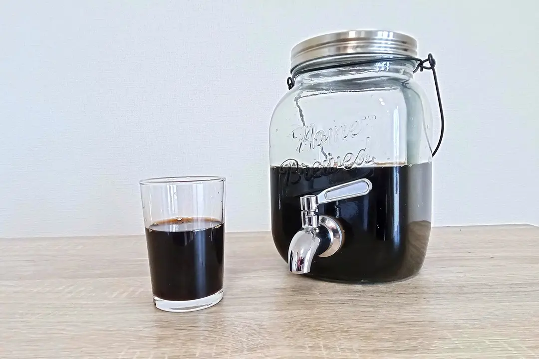 A glass of freshly poured coffee in a glass resting in front of the Willow & Everett cold brew coffee maker.
