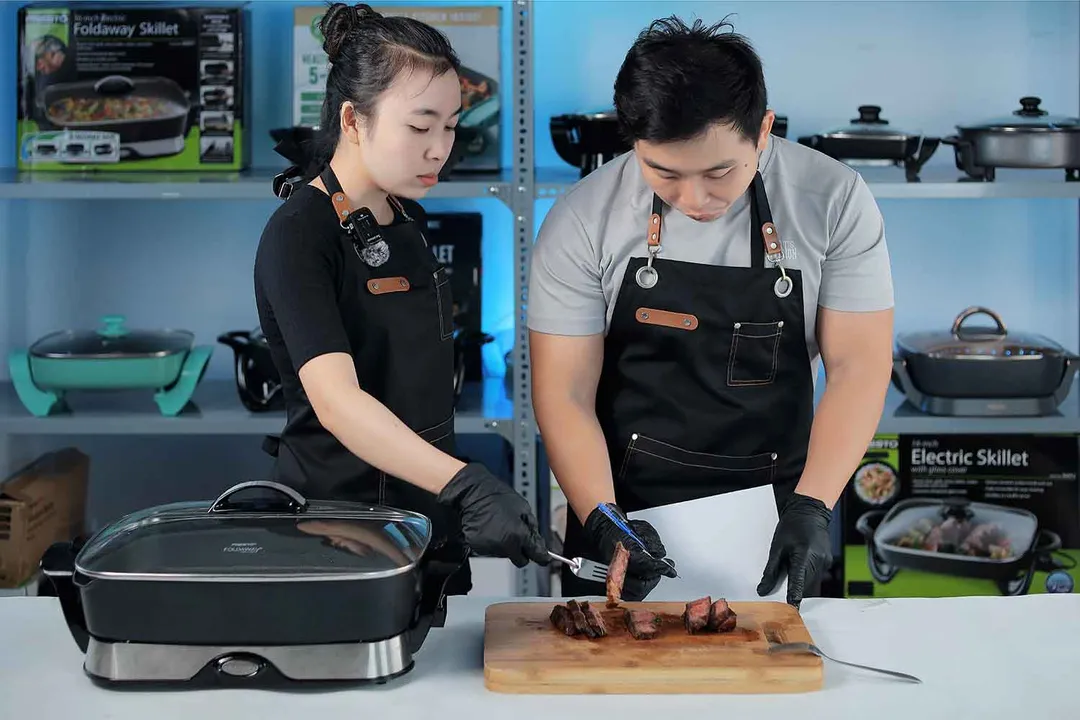 Two people tasting and evaluating a steak made with the Presto Foldaway Non-Stick Electric Skillet 06857.