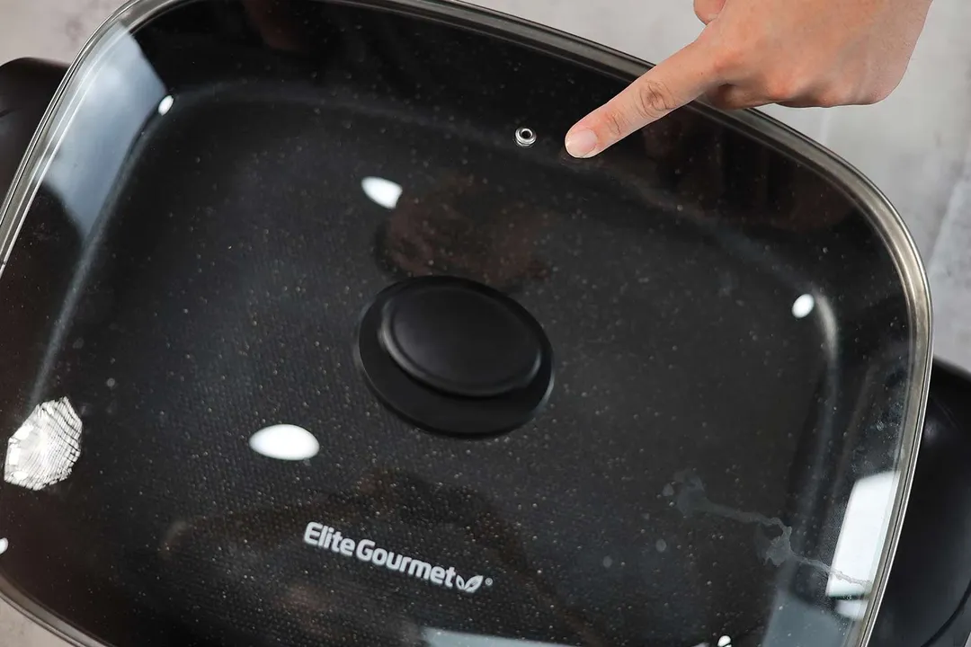 The tempered glass lid of the Elite Gourmet Non-Stick Electric Skillet EG-6203 has a steam vent.