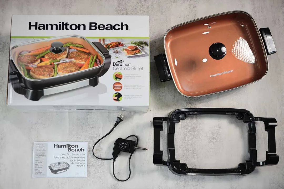On the upper right is the Hamilton Beach Ceramic Non-Stick Electric Skillet 38529K. On the left is its cardboard box. Below the skillet from right to left is an instruction manual, a thermostat, and a detachable base.