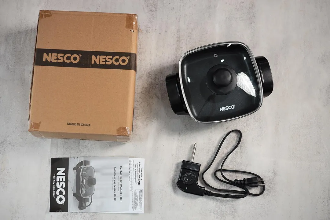 On the upper right is the Nesco Non-Stick Electric Skillet ES-08. On the left is its cardboard box. Below the skillet, on the right is a thermostat and on the left is an instruction manual.
