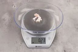 0.23 ounces of soft tissue and pieces of shredded cartilage, on digital scale, on granite-looking table.
