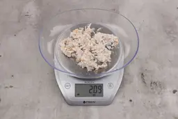 2.09 ounces of assorted fibrous tissue and shredded bones, on digital scale, on granite-looking table.