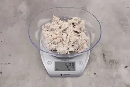 5.28 ounces of visible pin bones among mess of raw fibrous tissue on digital scale, on granite-looking table.