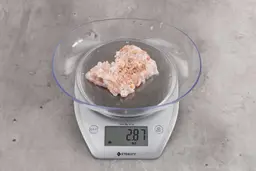 2.87 ounces of fibrous soft tissue and pieces of shredded bones, on digital scale, on granite-looking table.