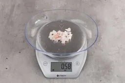 0.58 ounces of soft tissue and pieces of shredded cartilage, on digital scale, on granite-looking table.