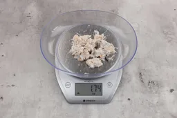 1.74 ounces of assorted fibrous tissues and shredded bones, on digital scale, on granite-looking table.