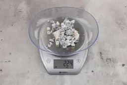 2.24 ounces of shredded fish skin among pieces of shredded spine, on digital scale, on granite-looking table.