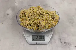 21.8 ounces of assorted ground scraps, including dietary fibers, bones, etc., on digital scale, on granite-looking top.