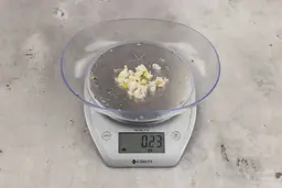 0.23 ounces of shredded pieces of fish backbone and lemon peels, on digital scale, on granite-looking top.