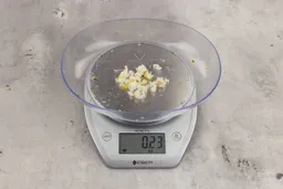 0.23 ounces of shredded pieces of fish backbone and lemon peels, on digital scale, on granite-looking top.