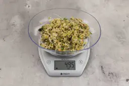 4.95 ounces of ounces of visible fish pin bones in mess of ground assorted scraps, on digital scale, on granite-looking top.
