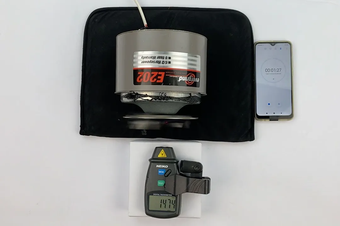 A digital tachometer is measuring the speed of the motor/flywheel of the Evergrind E202 1/2 HP Garbage Disposal in our speed test. A smartphone is running the timer app.