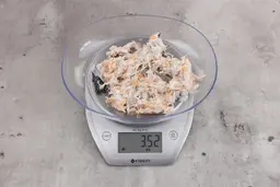 3.52 ounces of visible pin bones in a mass of raw meat and skin from fish scraps on digital scale on granite-looking top.