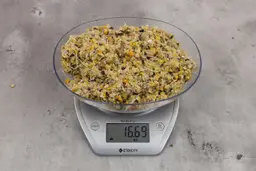 16.69 ounces of ground products from garbage disposal on digital scale on granite-looking table.
