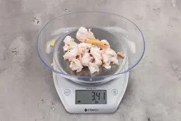 3.41 ounces of ground chicken scraps from a garbage disposal, displayed on digital scale, placed on granite-looking table. Mess of soft tissue and pieces of shredded cartilage.