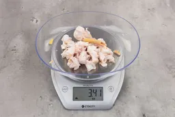 3.41 ounces of ground chicken scraps from a garbage disposal, displayed on digital scale, placed on granite-looking table. Mess of soft tissue and pieces of shredded cartilage.
