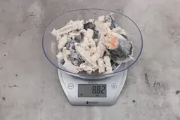 8.82 ounces of ground fish scraps from a garbage disposal, displayed on digital scale, placed on granite-looking table. Mess of shredded fish backbone and skin.