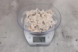 4.29 ounces of ground fish scraps from garbage disposal, displayed on digital scale, placed on granite-looking table. Pin bones among a mess of raw fibrous tissue.