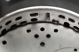 Inside view of GE Disposall GFC720N 3/4-hp garbage disposal, highlighting design of two-level grater/grinder ring, partially showing details of flywheel.