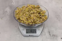16.55 ounces of ground products from a garbage disposal, displayed on digital scale, placed on a granite-looking table. Mess of assorted scraps, including fibers, bones, etc.